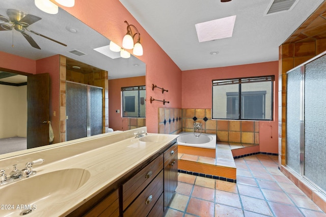 bathroom featuring a skylight, ceiling fan, vanity, and shower with separate bathtub