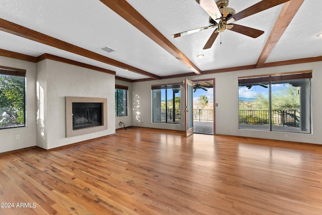 unfurnished living room with light wood-type flooring, a textured ceiling, and a healthy amount of sunlight