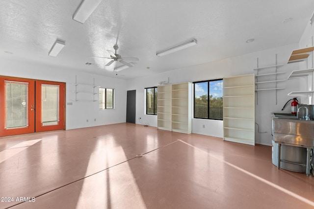 interior space featuring ceiling fan, french doors, concrete floors, and a textured ceiling