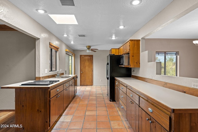 kitchen with a skylight, a textured ceiling, and appliances with stainless steel finishes