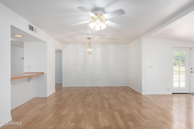 empty room with light wood-style floors, visible vents, ceiling fan with notable chandelier, and baseboards