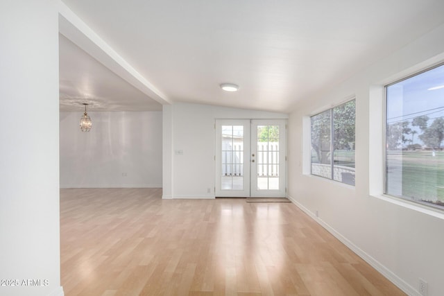 unfurnished room featuring french doors, baseboards, light wood finished floors, and an inviting chandelier