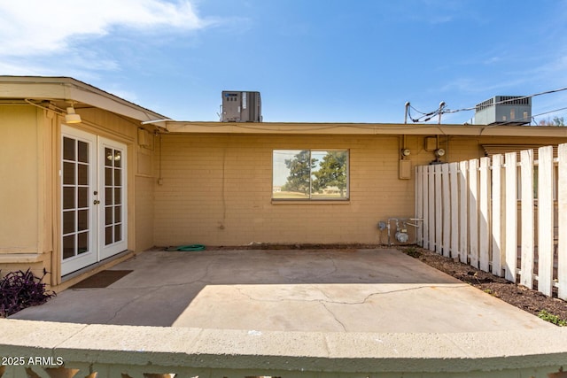 view of patio featuring french doors, cooling unit, and fence