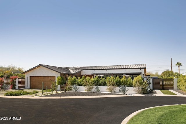 view of front of property featuring metal roof, a standing seam roof, fence, and stucco siding