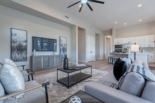 living room with ceiling fan and light hardwood / wood-style flooring