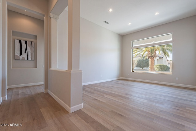 unfurnished room featuring ornate columns and light hardwood / wood-style flooring