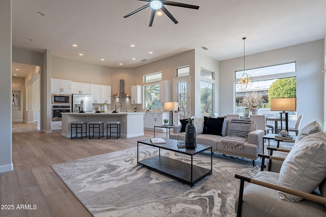 living room with light hardwood / wood-style floors, ceiling fan, and sink