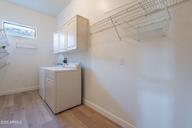 clothes washing area with cabinets, separate washer and dryer, and light hardwood / wood-style flooring