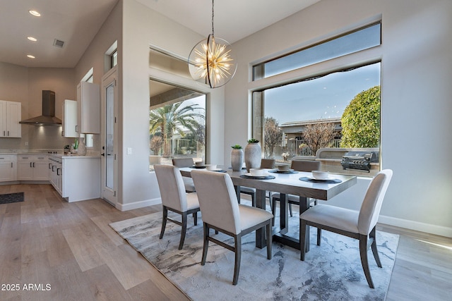 dining area featuring light wood-type flooring and a notable chandelier