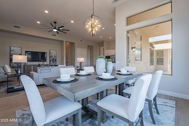 dining room with ceiling fan with notable chandelier and light wood-type flooring