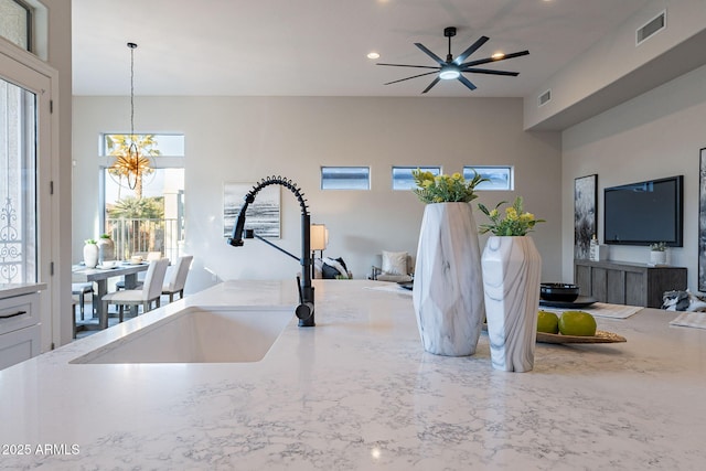 interior space featuring sink, pendant lighting, and ceiling fan with notable chandelier