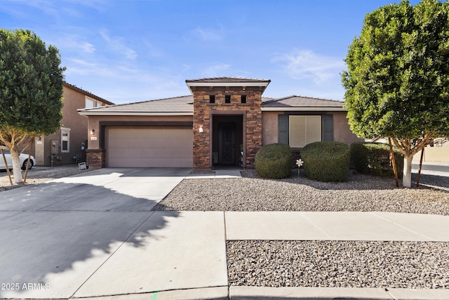 prairie-style home featuring a garage, stone siding, driveway, and stucco siding