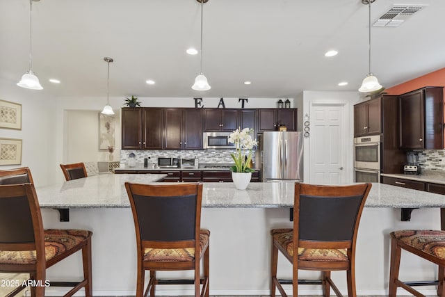 676 N 156th Ln, Goodyear, AZ 85338 - kitchen featuring appliances with stainless steel finishes, a spacious island, a breakfast bar area, and decorative light fixtures
