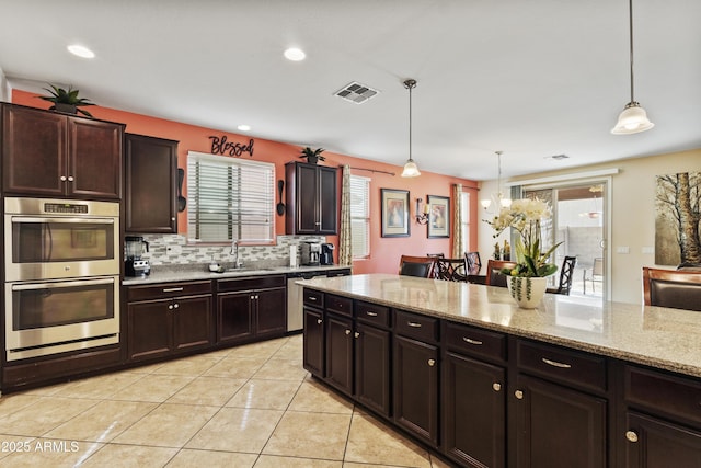 676 N 156th Ln, Goodyear, AZ 85338 - kitchen with stainless steel double oven, a sink, visible vents, backsplash, and decorative light fixtures