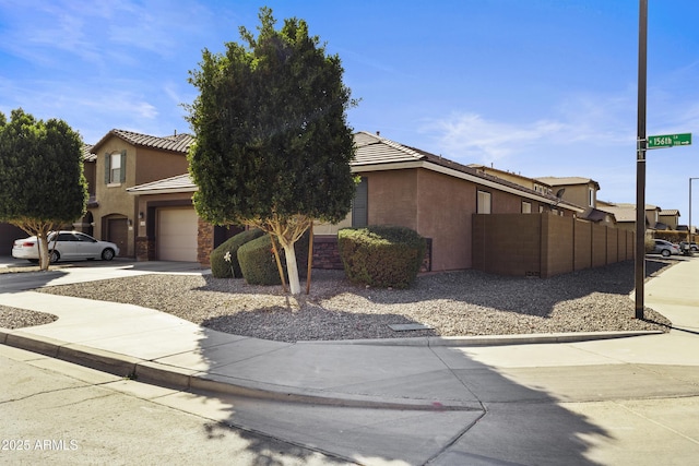 view of front facade featuring a garage, concrete driveway, a tile roof, and stucco siding