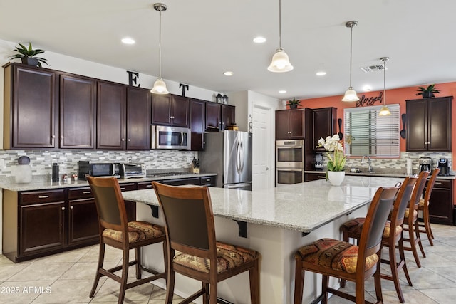 676 N 156th Ln, Goodyear, AZ 85338 - kitchen featuring appliances with stainless steel finishes, a breakfast bar area, a center island, pendant lighting, and a sink