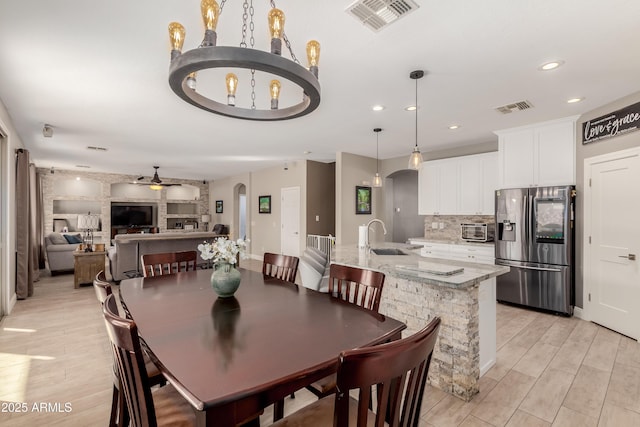 dining room featuring sink, ceiling fan with notable chandelier, and light hardwood / wood-style floors