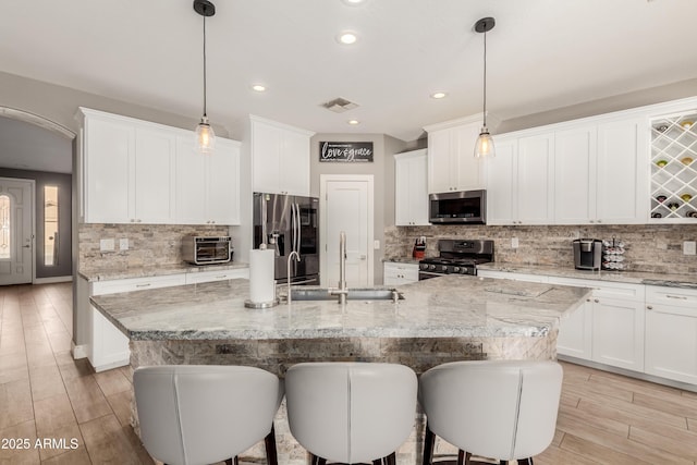 kitchen featuring an island with sink, appliances with stainless steel finishes, sink, and pendant lighting