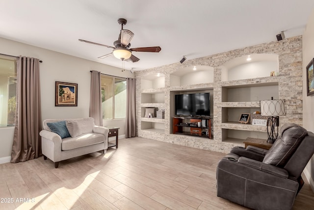 living room featuring light hardwood / wood-style flooring, built in features, and ceiling fan