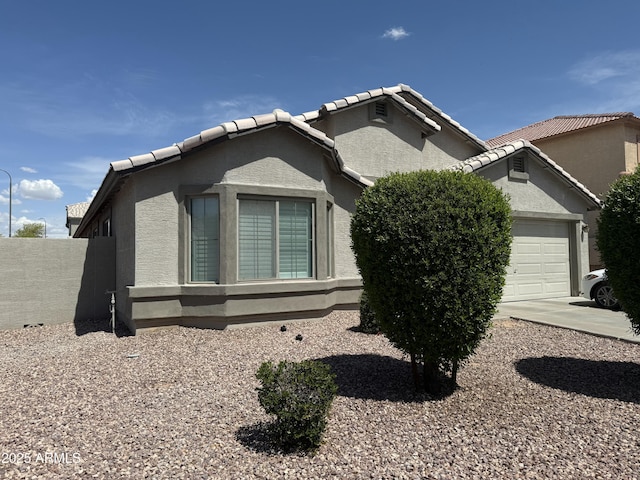 view of property exterior with an attached garage, a tile roof, and stucco siding