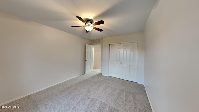 unfurnished bedroom featuring ceiling fan, light colored carpet, and a closet