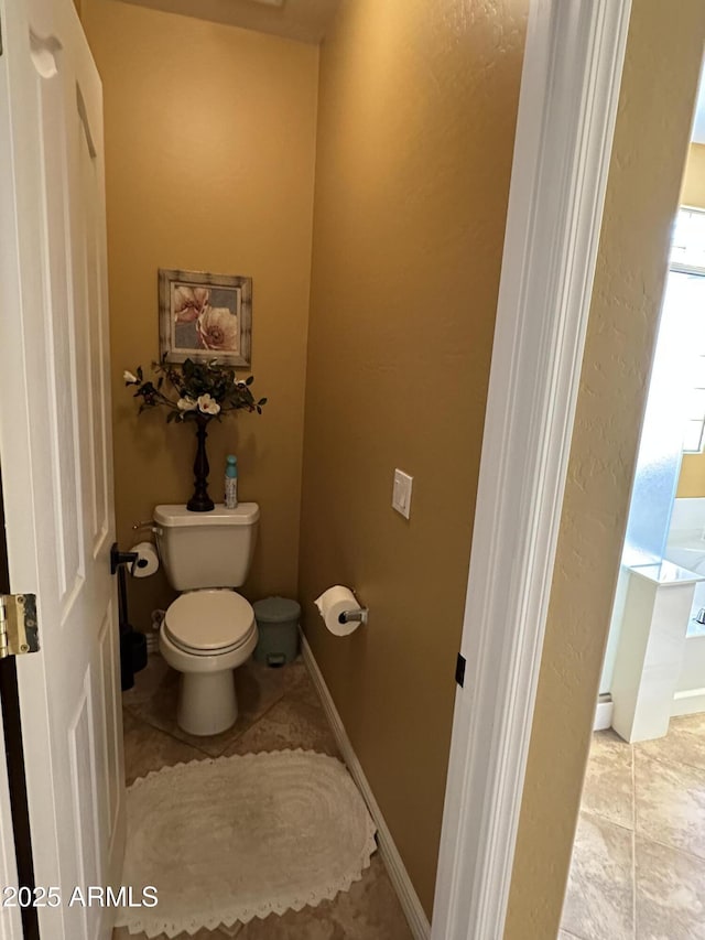 bathroom featuring tile patterned flooring, toilet, and baseboards