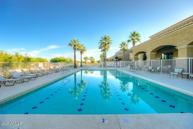 community pool with a patio area and fence