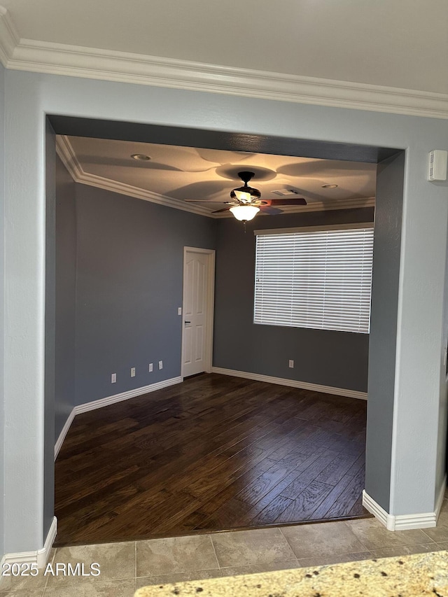 empty room featuring baseboards, wood finished floors, and crown molding