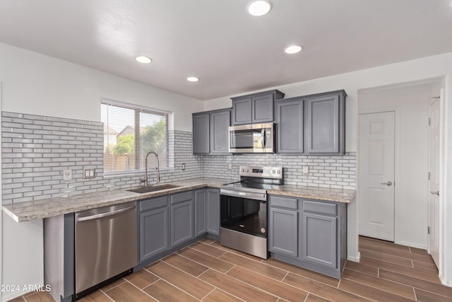 kitchen with dark wood-type flooring, sink, gray cabinets, and stainless steel appliances