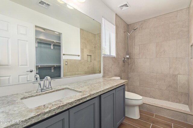 bathroom featuring vanity, toilet, and tiled shower