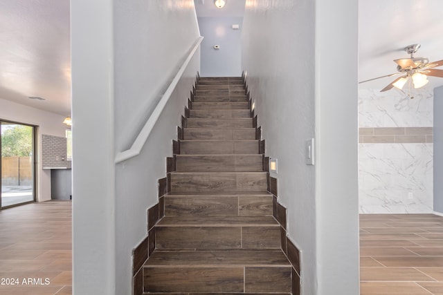 staircase featuring ceiling fan and wood-type flooring