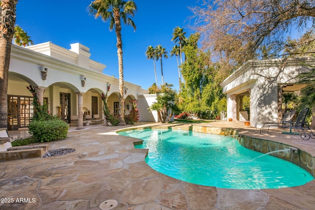 view of pool featuring french doors, pool water feature, and a patio area