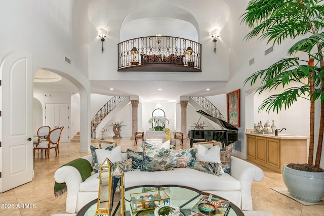 tiled living room featuring a towering ceiling and decorative columns