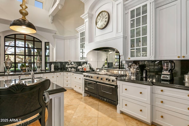 kitchen featuring decorative backsplash, white cabinets, and range with two ovens