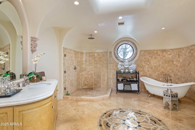 bathroom featuring vanity, independent shower and bath, and tile walls