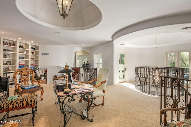 sitting room with a chandelier, light carpet, and a raised ceiling