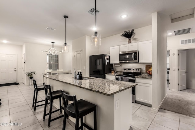 kitchen featuring white cabinetry, a kitchen island with sink, light stone countertops, and appliances with stainless steel finishes