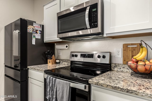 kitchen featuring stainless steel appliances, white cabinets, and light stone counters