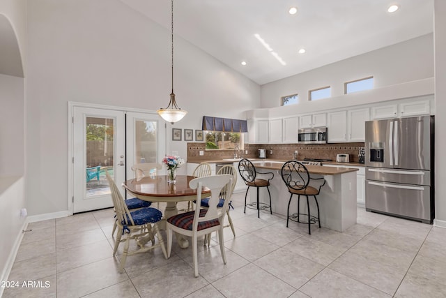 tiled dining space featuring high vaulted ceiling and french doors