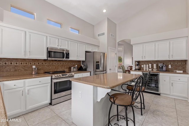 kitchen featuring white cabinetry, stainless steel appliances, beverage cooler, and a kitchen island