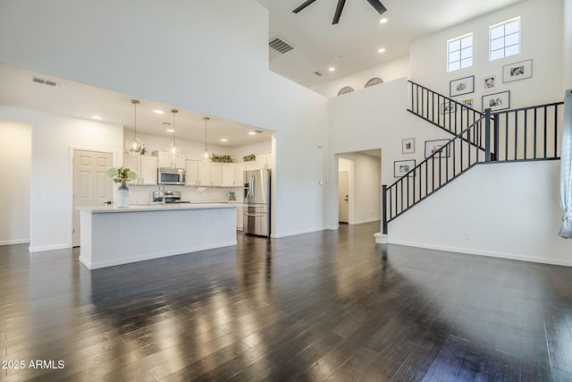 10925 E Toluca Ave, Mesa, AZ 85212 - unfurnished living room with a ceiling fan, dark wood-style flooring, stairs, a high ceiling, and baseboards