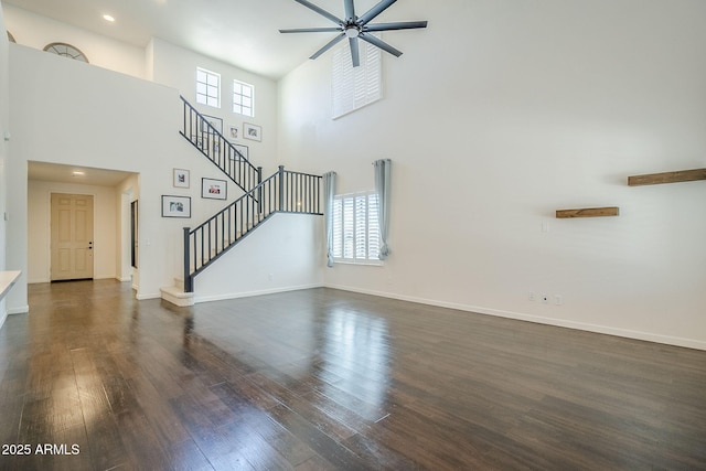10925 E Toluca Ave, Mesa, AZ 85212 - unfurnished living room featuring dark wood-style floors, ceiling fan, stairway, baseboards, and a towering ceiling