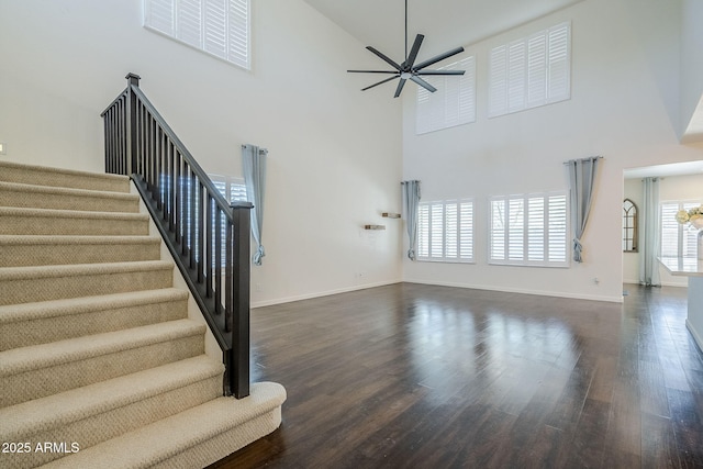 10925 E Toluca Ave, Mesa, AZ 85212 - unfurnished living room with a towering ceiling, ceiling fan, stairs, dark wood-style floors, and baseboards