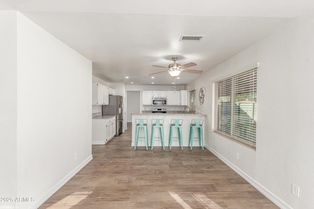3805 E Desert Flower Ln, Phoenix, AZ 85044 - kitchen featuring appliances with stainless steel finishes, a breakfast bar, white cabinets, a peninsula, and a ceiling fan