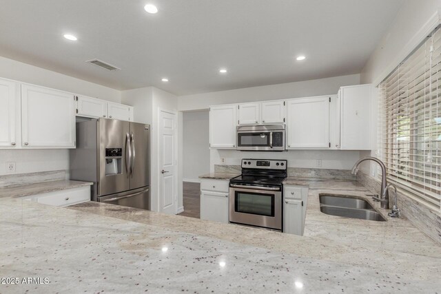 3805 E Desert Flower Ln, Phoenix, AZ 85044 - kitchen featuring appliances with stainless steel finishes, a sink, light stone counters, white cabinets, and recessed lighting