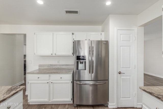 3805 E Desert Flower Ln, Phoenix, AZ 85044 - kitchen with stainless steel fridge with ice dispenser, white cabinets, light stone counters, baseboards, and light wood-style flooring