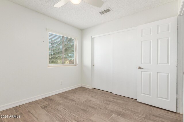 3805 E Desert Flower Ln, Phoenix, AZ 85044 - unfurnished bedroom with a textured ceiling, light wood finished floors, a closet, ceiling fan, and baseboards