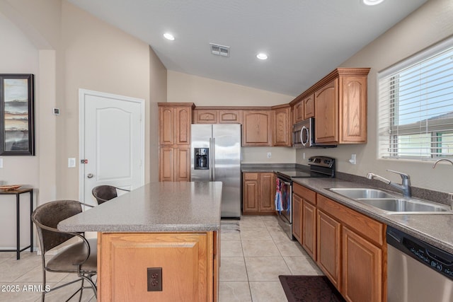 kitchen with vaulted ceiling, a breakfast bar area, appliances with stainless steel finishes, a center island, and sink