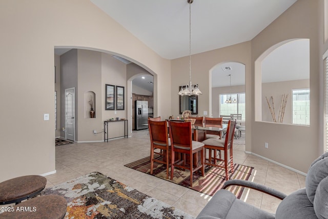 tiled dining area featuring high vaulted ceiling and an inviting chandelier