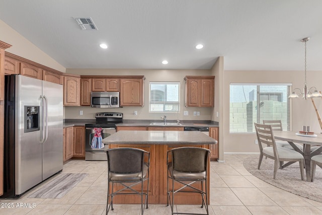 kitchen with appliances with stainless steel finishes, a center island, light tile patterned floors, a notable chandelier, and sink